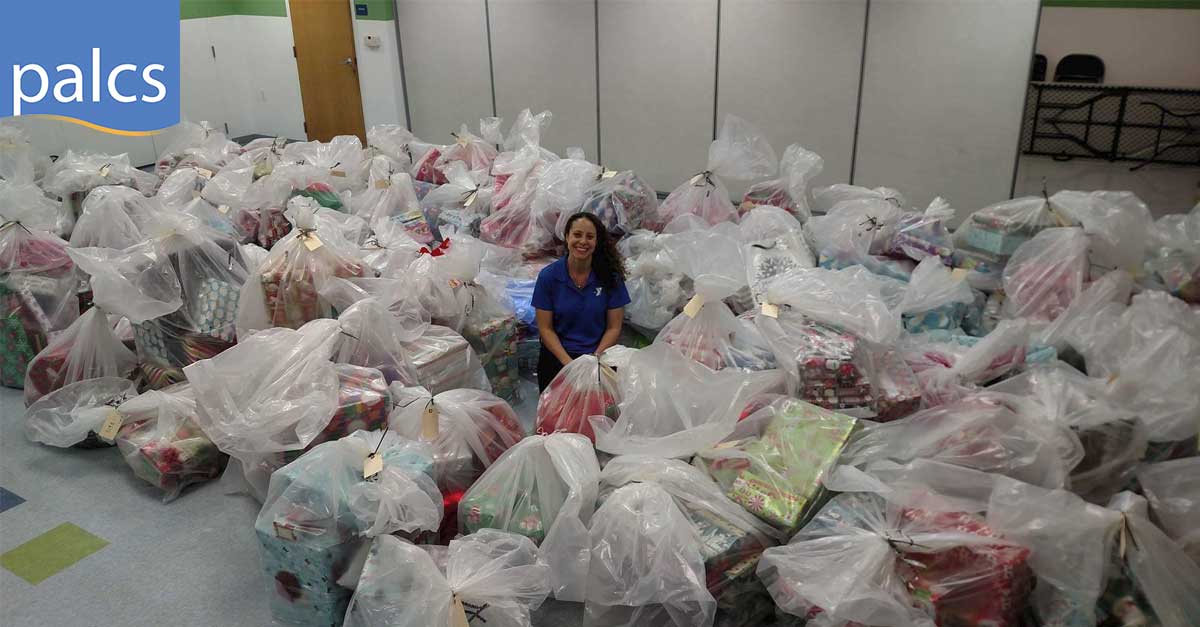 Charity work, staff members sponsor gifts for children, a teacher surrounded by bags of wrapped presents