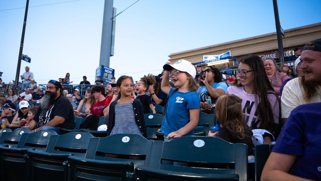 Two girls cheering from the stands during the IronPigs baseball game.
