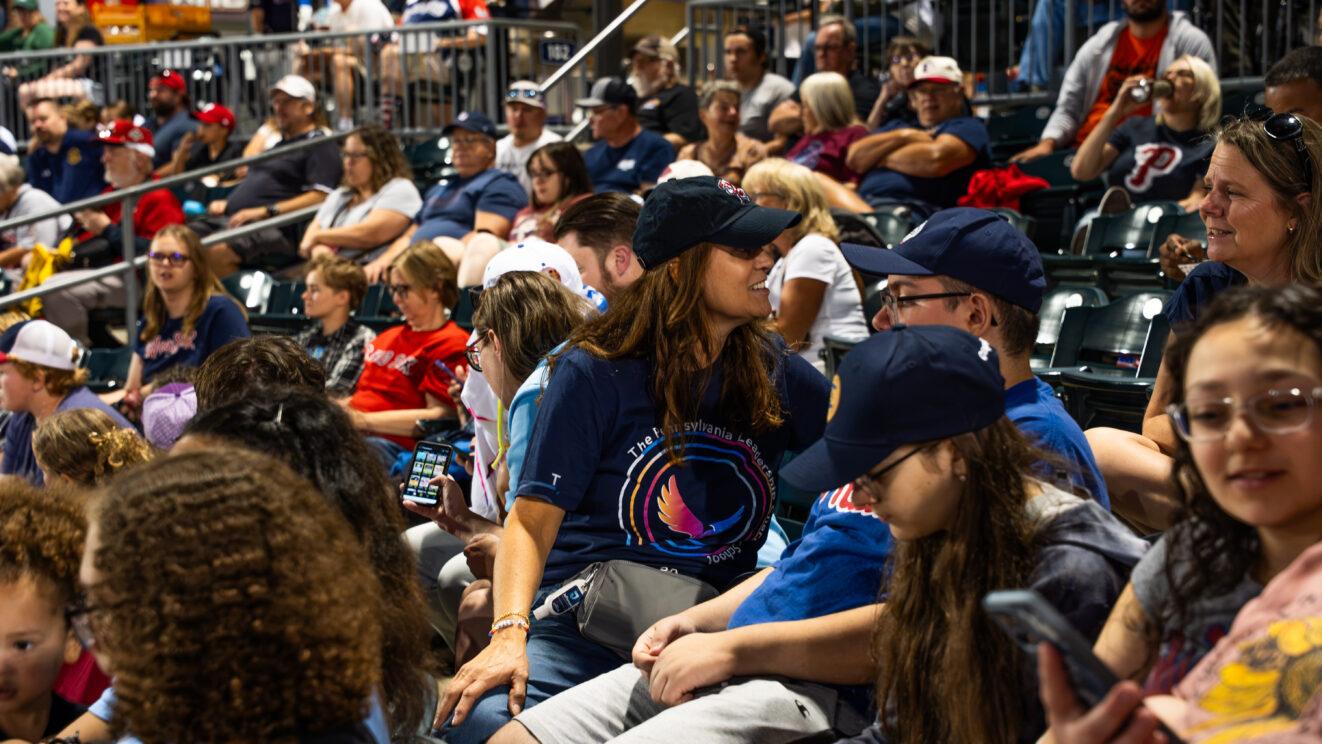 A PALCS staff members talks to someone while seated in a group of PALCS families.